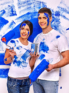 新婚快乐的新婚夫妇在家里画蓝色的墙图片