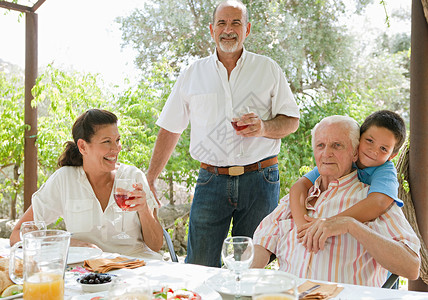一群快乐的家庭成员在避暑别墅度假时在别墅绿色花园享用西班牙小吃图片