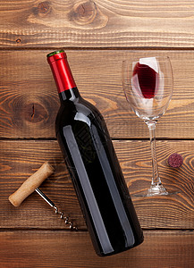 木桌背景上的红酒瓶玻璃和开瓶器顶视图图片