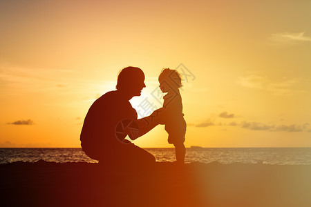 在日落海滩牵手的父亲和小女儿剪影图片
