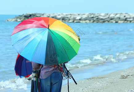 夏天在海滩上卖五颜六色的雨伞的老小贩背景图片