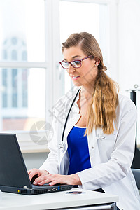 年轻女医生坐在窗前的办公桌前图片