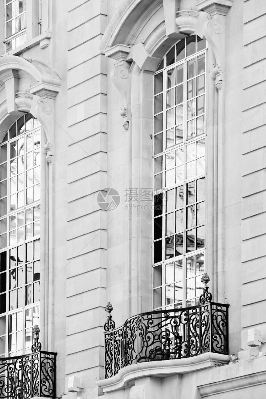 用大窗户和反光玻璃关闭伦敦市一座具有复杂特征和装饰细节的旧石建筑的静物细节视图经典图片