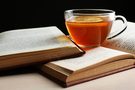 玻璃杯茶木桌上放着打开的书特写图片