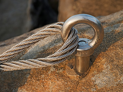 砂岩石中钢螺栓锚眼的细节钢丝绳的末端结通过ferrata的登山者路径铁背景图片