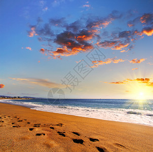 海滩旅行日落时在沙滩上的沙滩上留下脚印旅图片