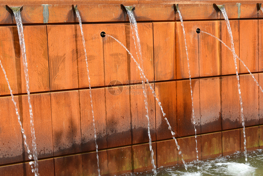 现代喷泉水从金属橙色面板中流出图片