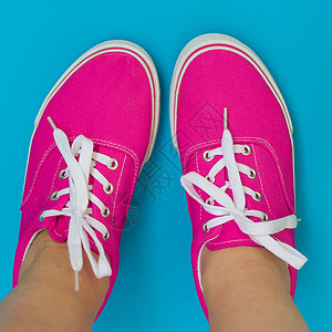 蓝色背景上穿着粉色运动鞋的腿图片