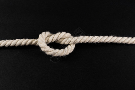 用白色绳子绑在黑色工作室背景图片