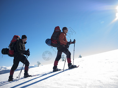 雪鞋的朋友和大背包在冬天穿山图片