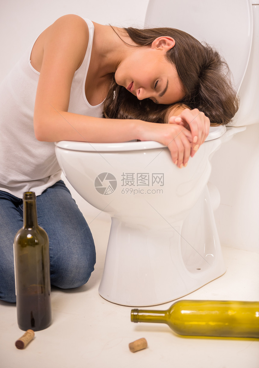 喝醉的女人坐在马桶地板上拿着一图片