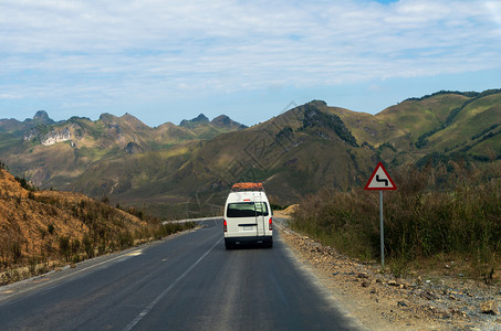 老挝公路上有交通标志和山地背景的旅游图片