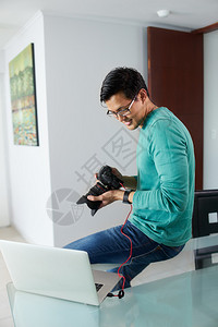 男子通过USB电缆将数码单反相机连接到笔记本电脑图片