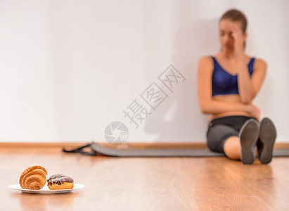 年轻悲伤的女人坐在地板上专心吃甜食图片