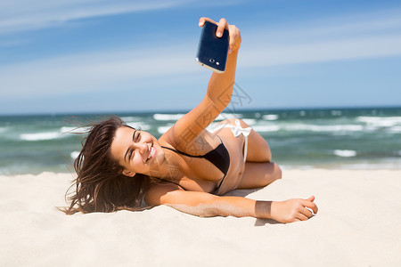 年轻女子在海滩放松时自拍图片