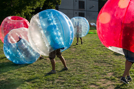青少年在BubbleBumb新而有趣的户外团队游戏中玩耍孩子们都生活在被吹散的塑料透明泡沫内背景图片