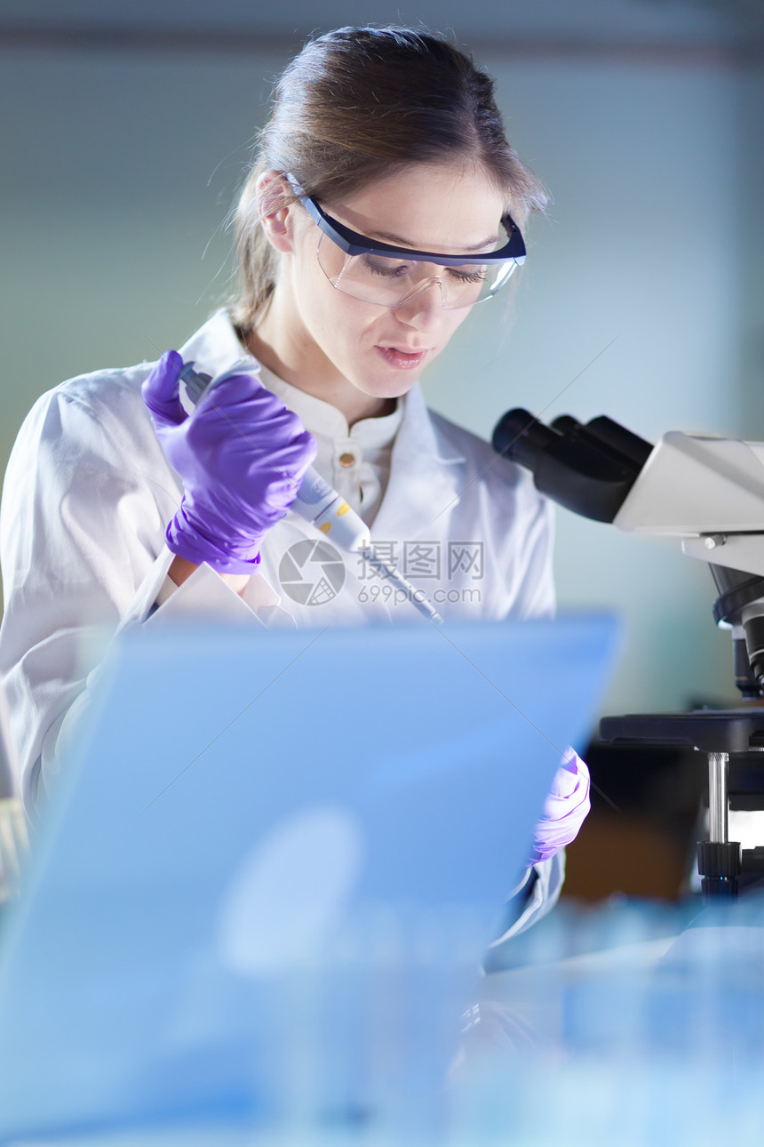 在实验室研究的生命科学家在他的工作环境中显微镜下有吸引力年轻自信的女保健专业人员移液的画像医疗保图片