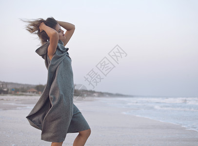 穿着毛衣的年轻美女在海面岸散步放图片