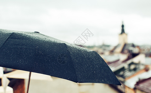 在旧城背景上有雨滴的伞图片