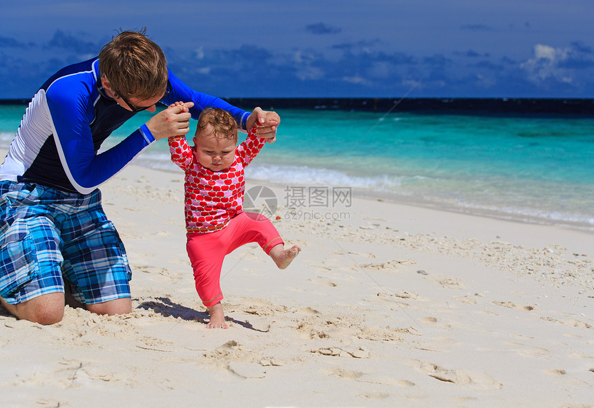 父亲和小女儿在沙滩上学走路图片