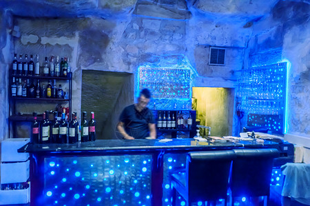 酒吧里的酒保周围环绕着带有蓝光的酒瓶图片