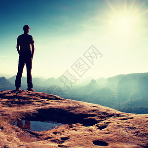 独自一人戴着红帽的徒步旅行者站在岩石帝国公园的砂岩峰顶上图片