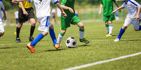 年轻男孩玩足球比赛两个球队的跑步选手白制图片