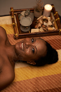 快乐的非裔美国女人的肖像躺在按摩床上图片