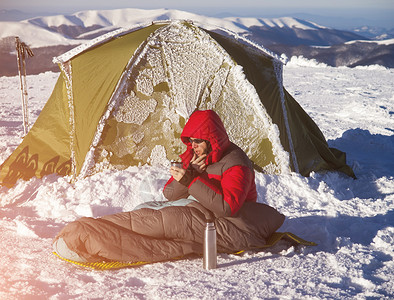 一名男子坐在帐篷附近的睡袋里图片