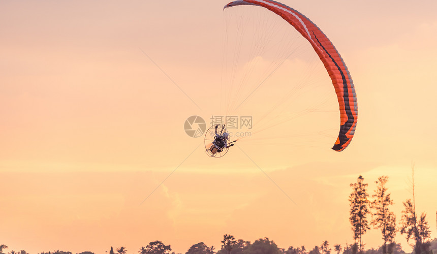 在夕阳的天空中飞行的动力伞图片