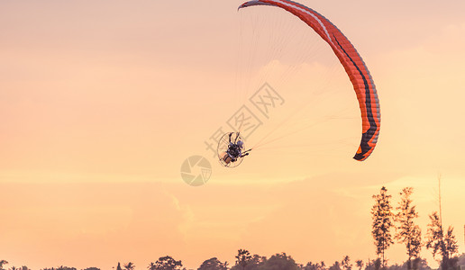 在夕阳的天空中飞行的动力伞图片
