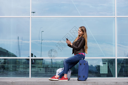 一名坐在袋子上看手机的年轻旅图片