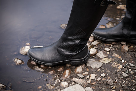 黑皮鞋高靴在雨坑闭合有选择地聚焦图片