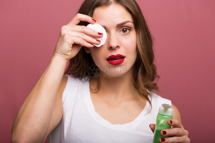 女人用乳液和化妆棉清洁她的脸图片
