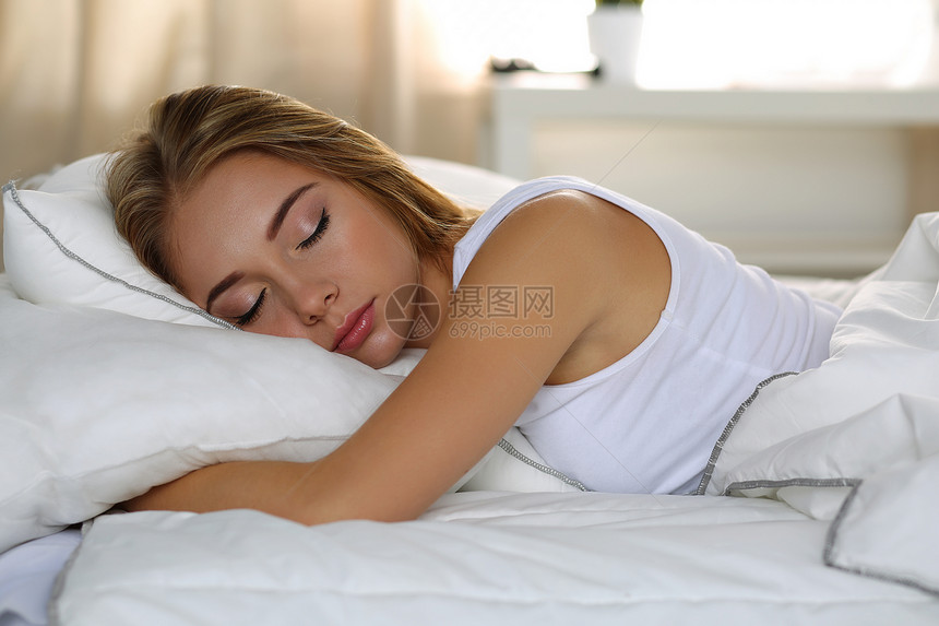 年轻美丽的金发女人肖像躺在床上图片