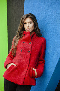 穿红大衣的年轻姑娘仰在蓝墙背景图片