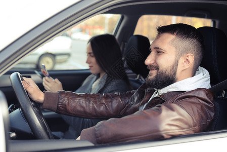 微笑的年轻男子驾驶汽车女人在智图片