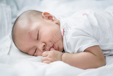 亚洲婴儿睡在白色床单上图片