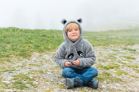 可爱的小男孩在雾的一天户外玩耍穿着有趣图片
