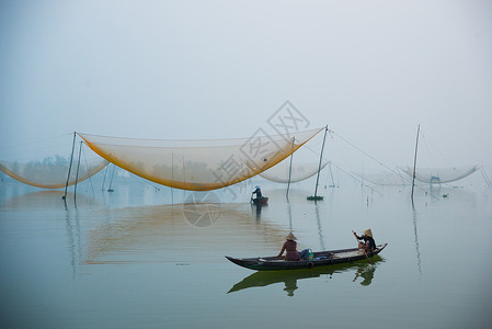 不明身份的渔民清晨在越南霍安河上检查自己的渔网图片