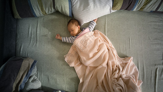 坐在父母大床上的可爱新生婴儿男孩图片