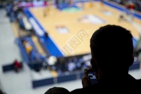 一个职业篮球比赛的观众在半场时在他的手机上写了个信息校对图片