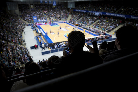 专业篮球比赛的观众在半场时间看他的手机背景图片
