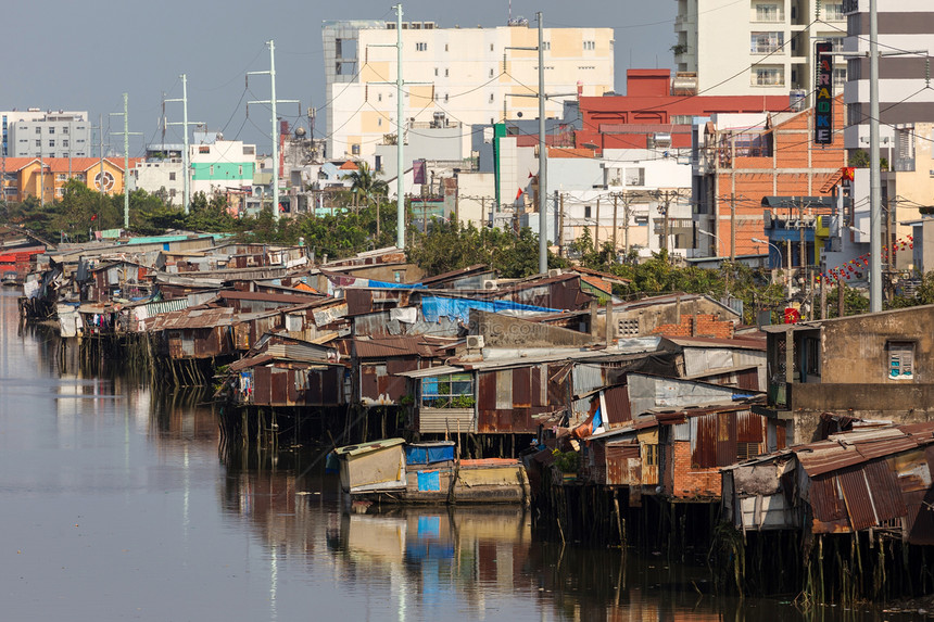 在越南胡志明市现代建筑前的西贡河岸贫民窟木制房屋图片