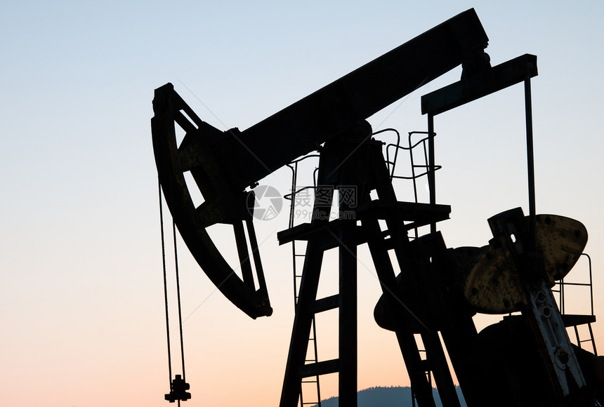 夕阳天空下的石油和天然气井图片