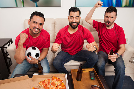 三位男朋友和足球迷在电视上观看比赛时图片