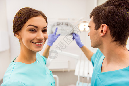 牙医和助理医生在防护手套上检查下巴的X光分图片
