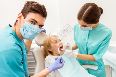 由牙医和助理向小女孩提供牙科检查的图像图片