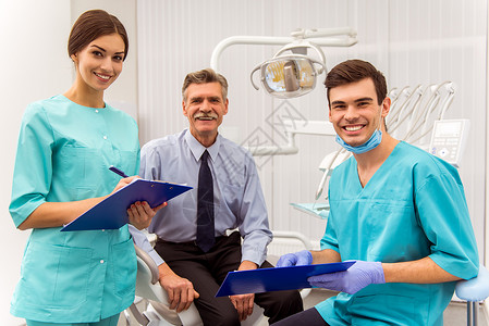 年轻医生牙医和他的助手记录在文件中一位坐在牙图片