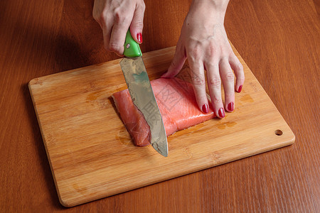 厨师在木制砧板上切鲑鱼片图片